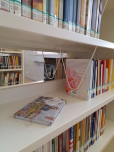 Vista parcial das estantes da biblioteca com um dos livros desta iniciativa.