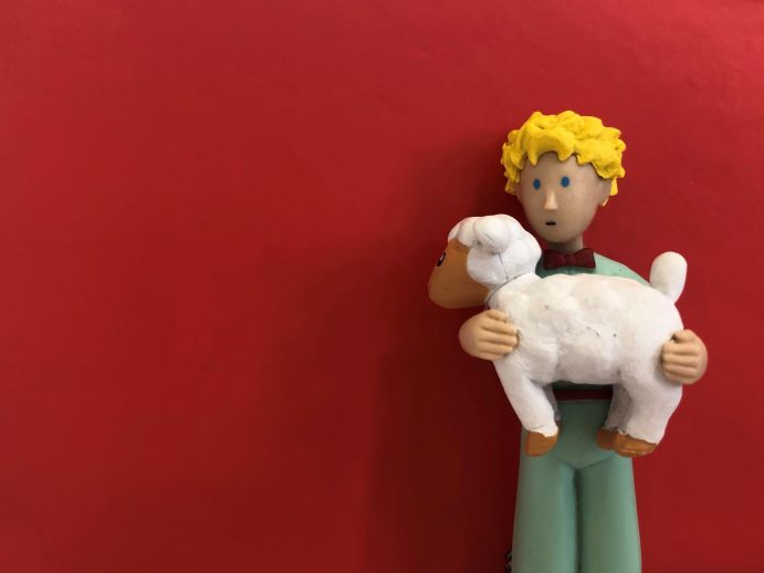 Fotografia de um boneco com uma ovelha ao colo.