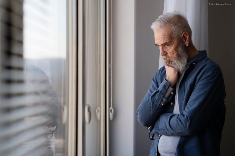 Imagem de um homem à janela, pensativo.