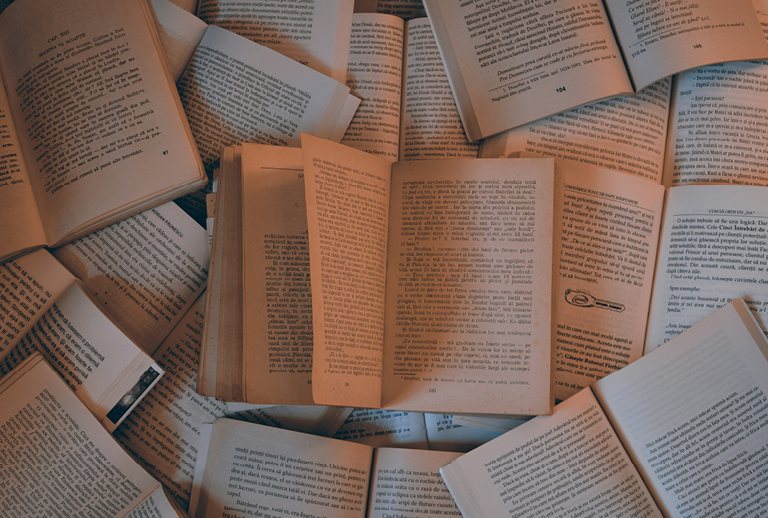 Imagem com vários livros abertos.
