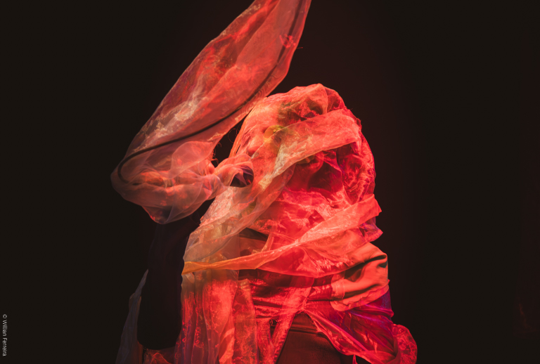 Imagem com uma artista da peça envolta em panos